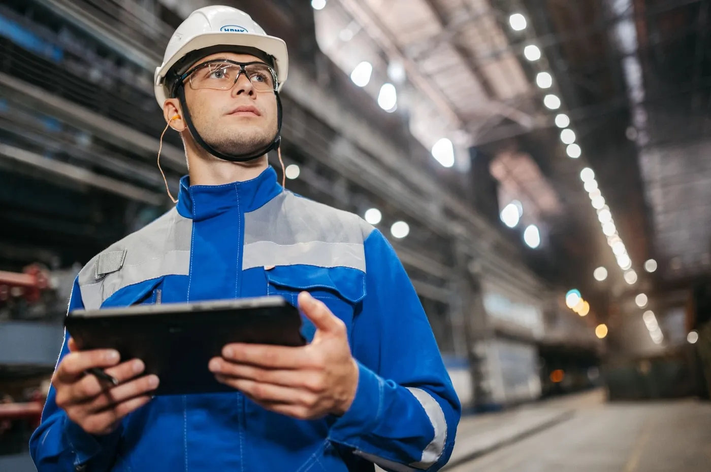 Factory worker in a hard hat holding a tablet on the shop floor