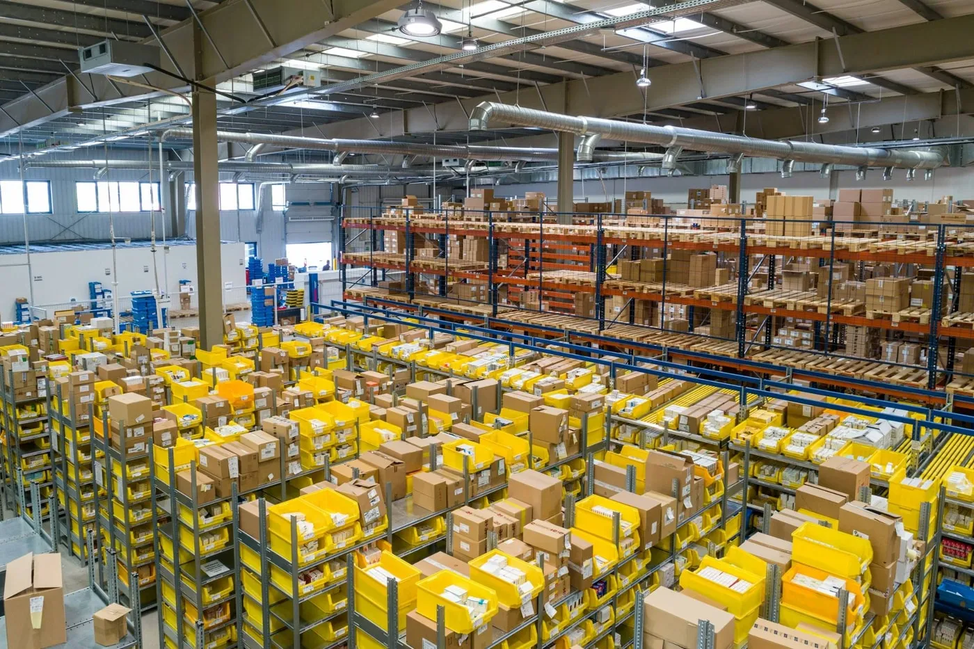 Warehouse with shelves of yellow bins, boxes and pallet racking