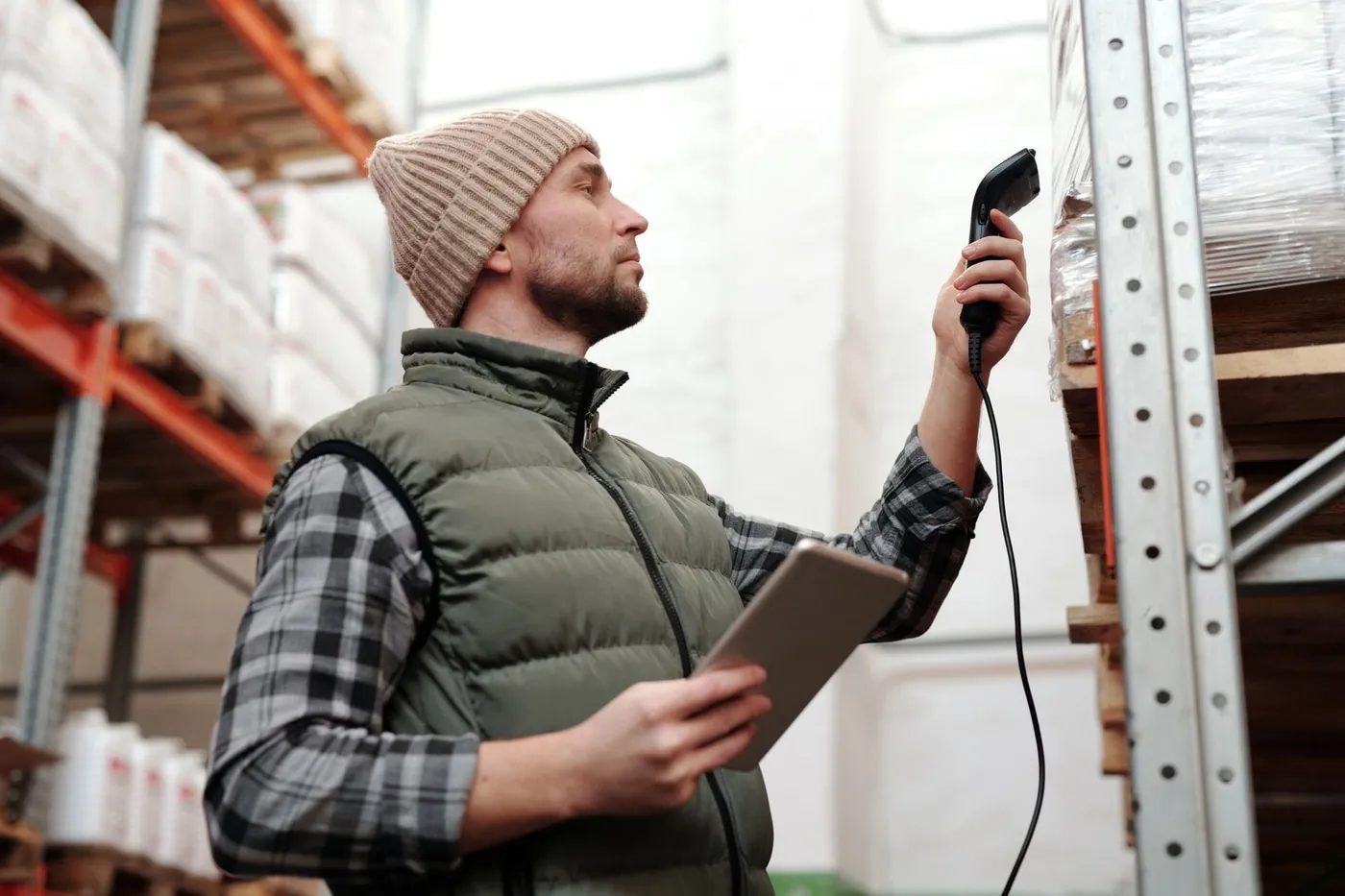 Warehouse worker scanning a pallet barcode while holding a tablet